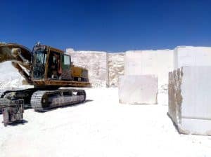 Excavator working in an Egyptian marble quarry beside large raw marble blocks